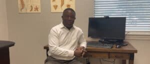 Man sitting in office with computer and spine charts.