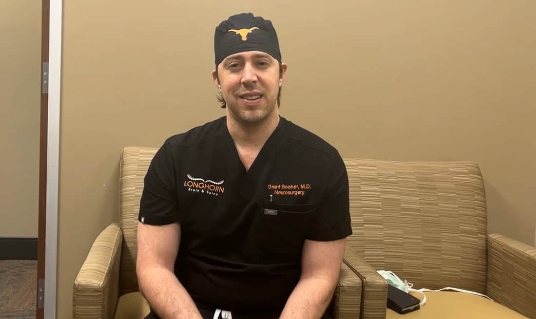 Doctor in scrubs sitting on chair indoors.
